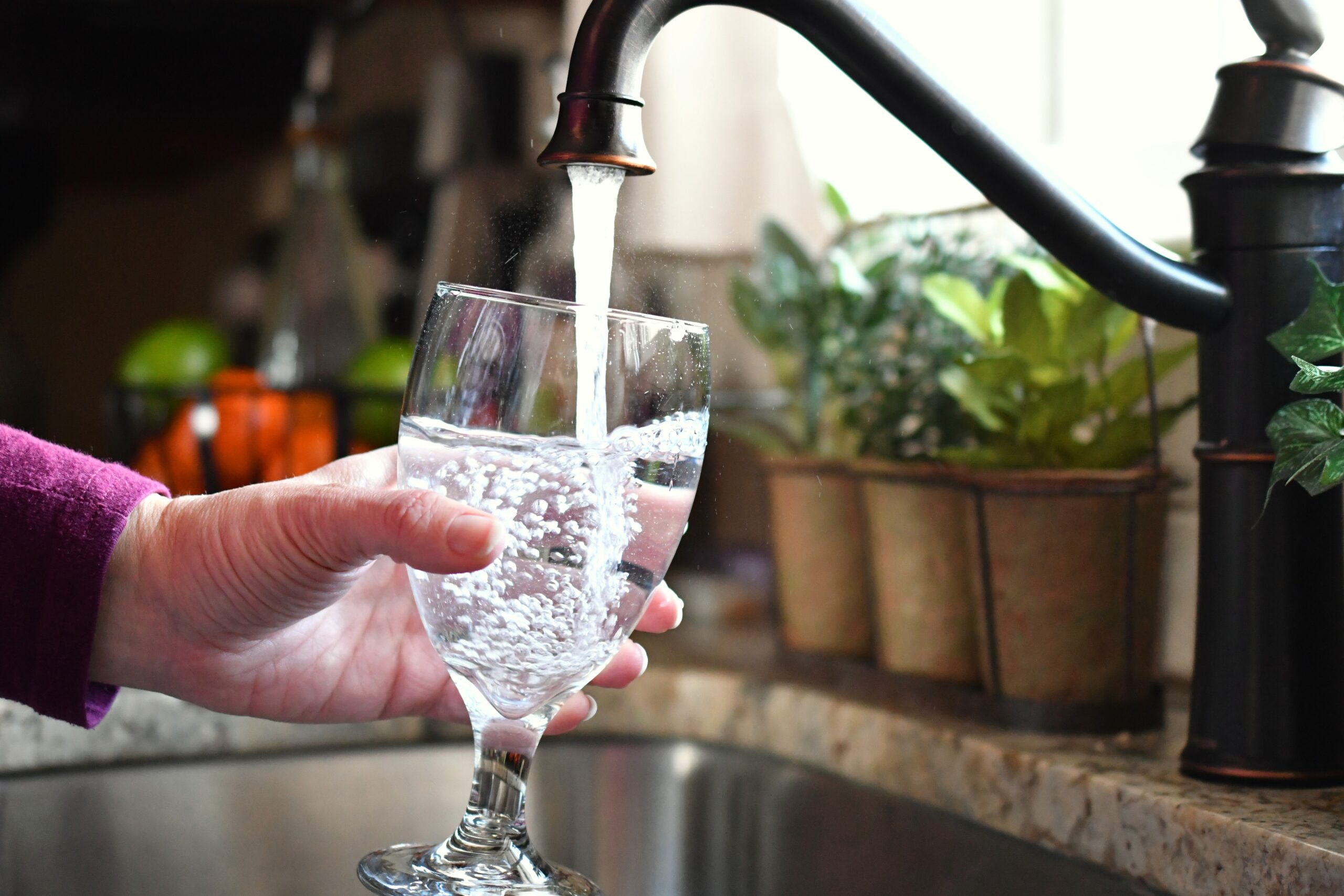 clean water public health - Woman fills a glass goblet with clean water, highlighting its importance for public health and co